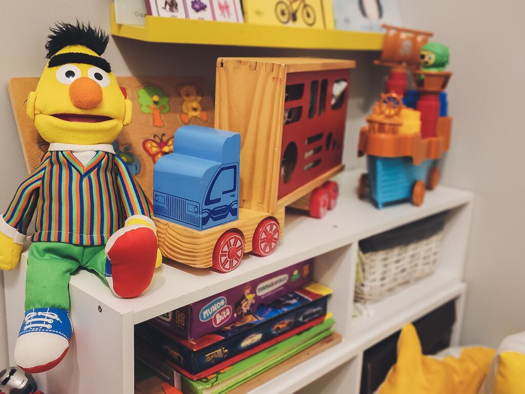Detalhe da estante com livros infantis, jogos e brinquedos de madeira.