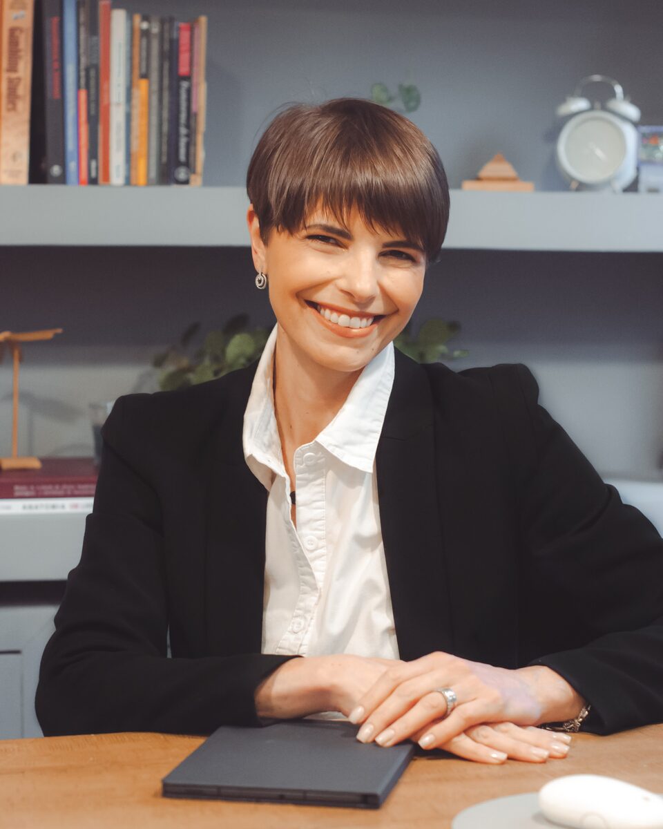 Danielle Rossini, psicóloga e neuropsicóloga, sentada à mesa de seu consultório.